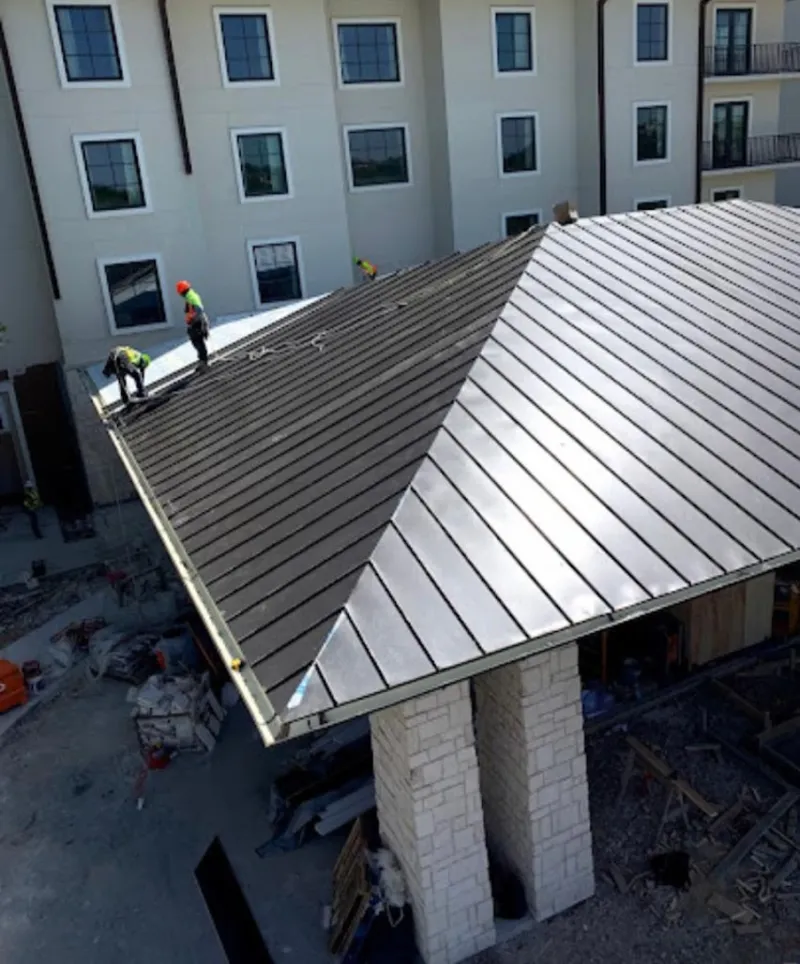 Crew installing standing seam metal roof panels on a commercial project in Little Falls